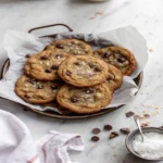 Banana bread cookies recipe with chocolate chips and sea salt served on parchment paper in a rustic tray