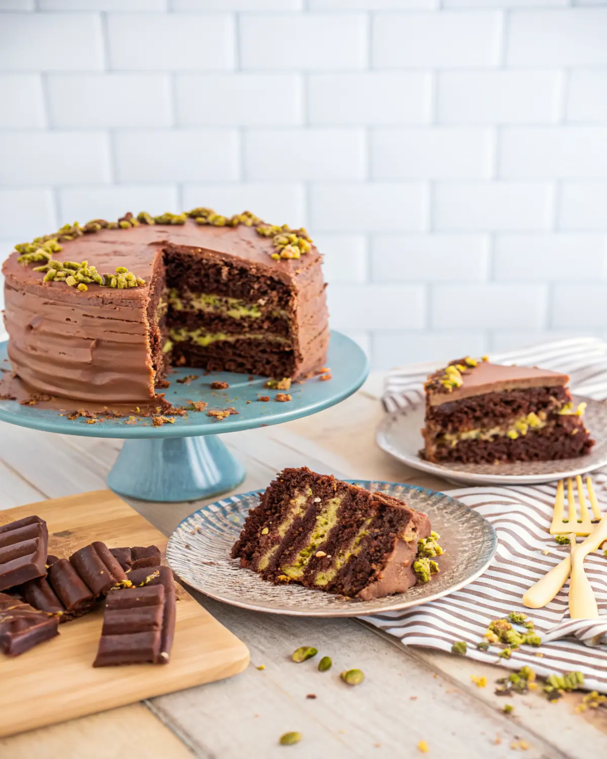 dubai-chocolate-cake-pistachio-layers-sliced Dubai Chocolate Cake with chocolate frosting and pistachio layers served on plates