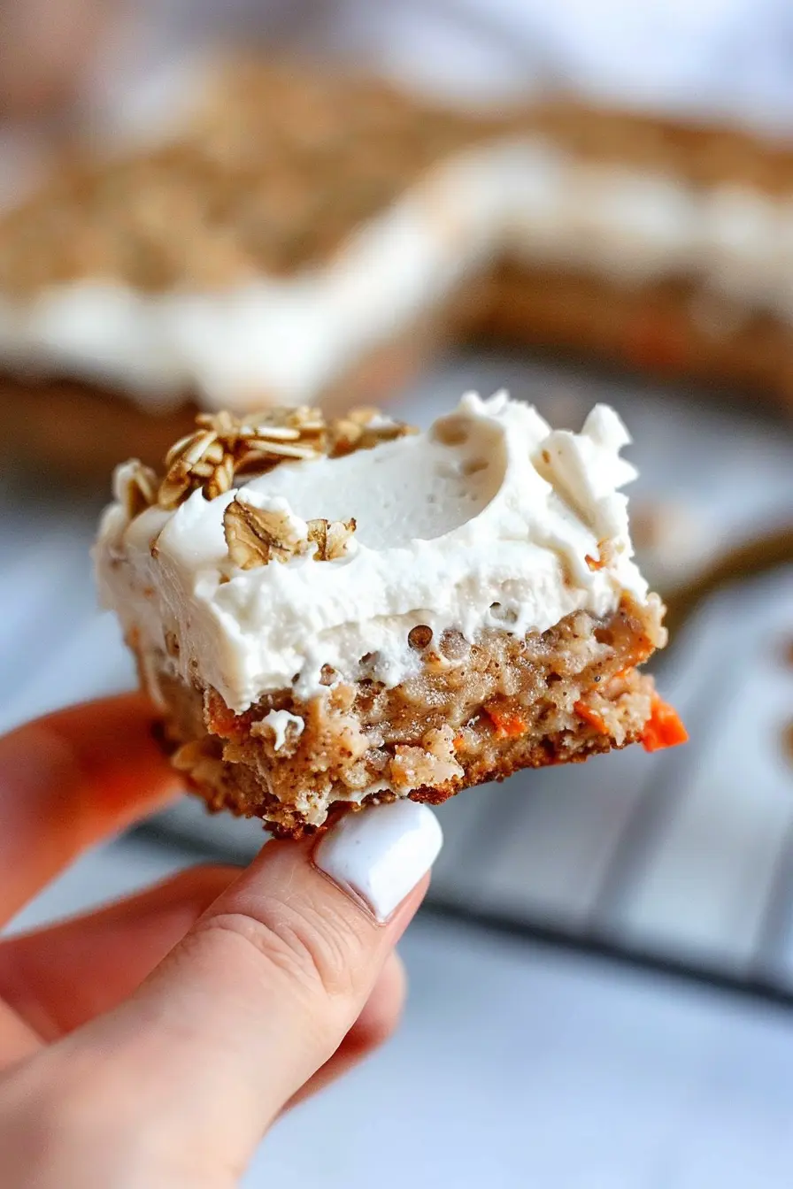 healthy-cream-cheese-frosted-carrot-bar Hand holding a carrot oat bar with healthy cream cheese frosting