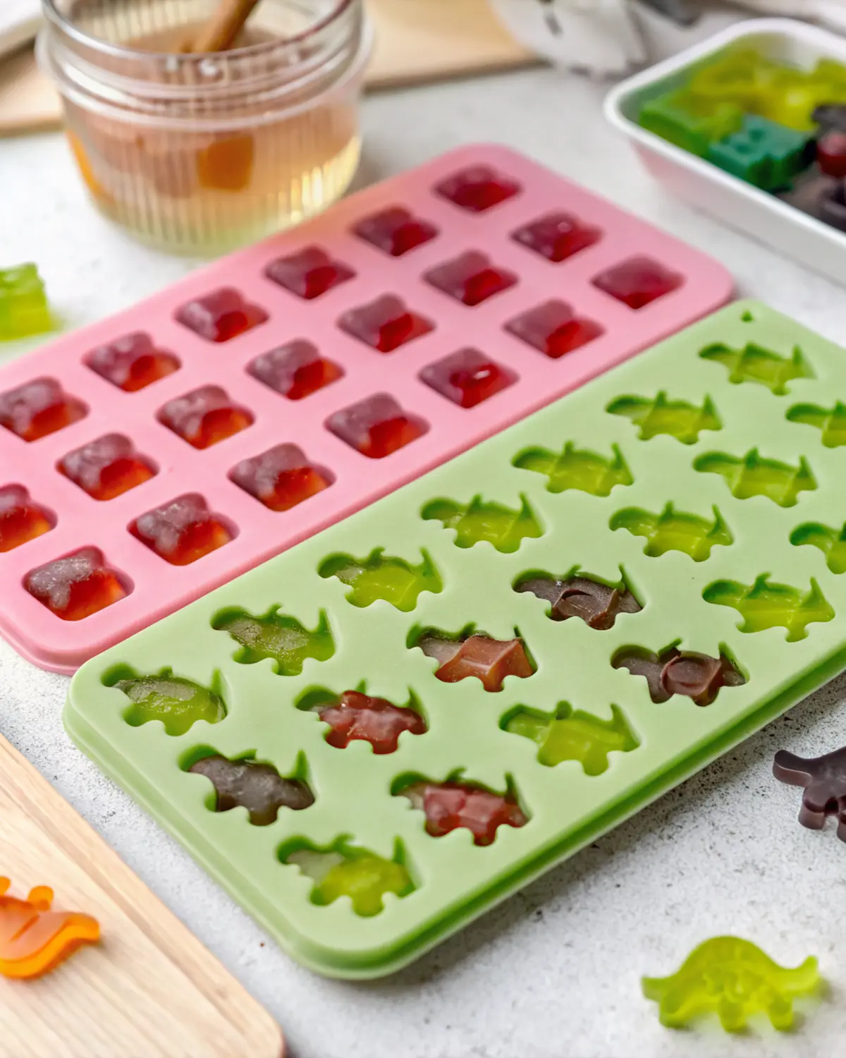 healthy-jelly-sweets-dino-mold Green silicone mold filled with dinosaur-shaped healthy jelly sweets in assorted natural colors